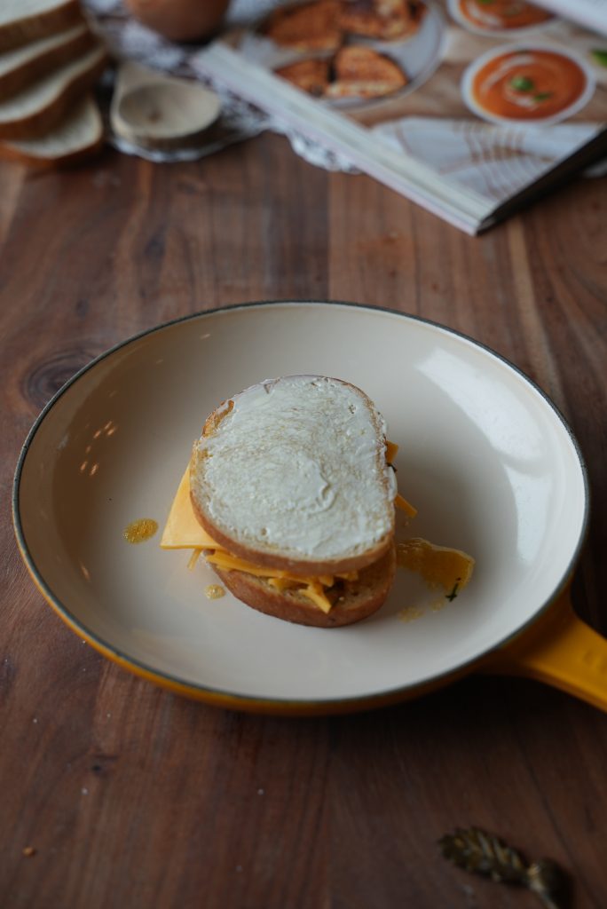 A grilled cheese going into the skillet, mayo-side up