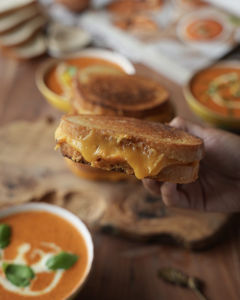 Holding a halved garlic bread grilled cheese with melted cheese