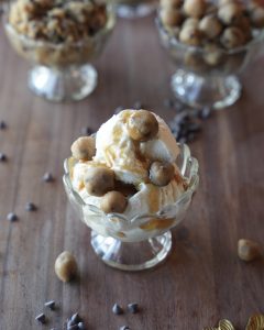 Salted brown butter edible cookie dough bites on vanilla ice cream with caramel in a glass dessert cup