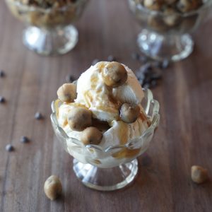 Salted brown butter edible cookie dough bites on vanilla ice cream with caramel in a glass dessert cup